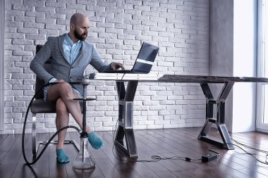 Pantolonu olmayan bir adam bilgisayarda, laptopta, mizah koronavirüsünde külot içinde çalışıyor.
