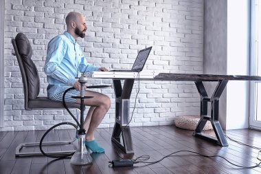 Pantolonu olmayan bir adam bilgisayarda, laptopta, mizah koronavirüsünde külot içinde çalışıyor.