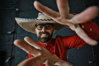 Hasır şapkalı bir adam stüdyoda elleri ve parmaklarıyla işaret ediyor. Batı Amerika Meksika Sambrero tarzı