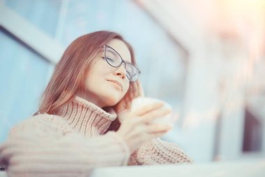 Bahar kafesi portresi, bir fincan kahveyle poz veren mutlu genç manken, bahar bakışı.