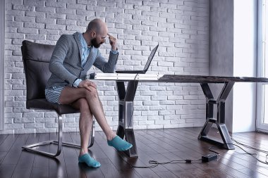 Pantolonu olmayan bir adam bilgisayarda, laptopta, mizah koronavirüsünde külot içinde çalışıyor.