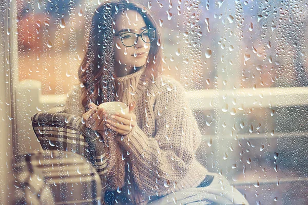 雨の日の秋のコーヒー熱いコーヒーを飲みながらガラスの後ろの女の子 — ストック写真