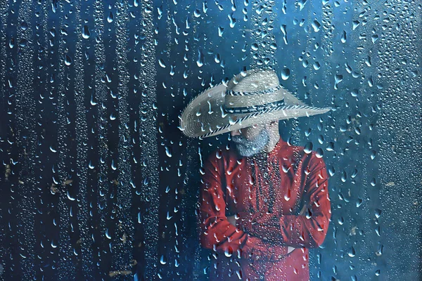 farmer in a straw hat behind glass rain drops, america wild west seasonal weather