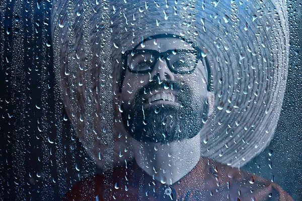 farmer in a straw hat behind glass rain drops, america wild west seasonal weather