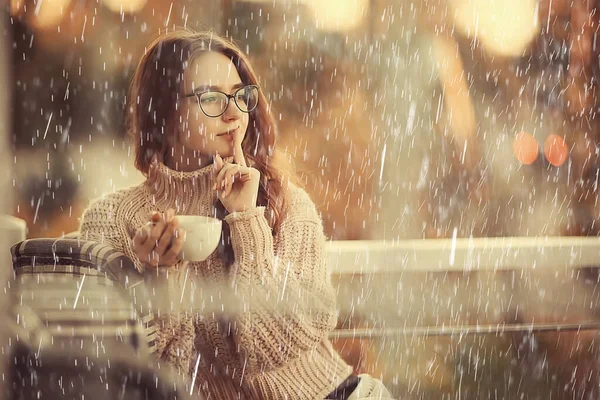 autumn coffee on a rainy day, girl behind a glass with a cup of hot coffee