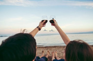 İki elle gözlük şarap ile deniz arka planda tutan