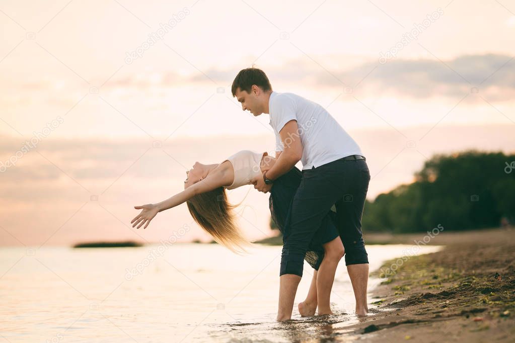 Young happy couple kiss on seashore