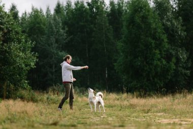 Genç adam doğa adlı köpeğiyle oynuyor.