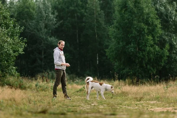 Молодой человек играет со своей собакой на природе . — стоковое фото