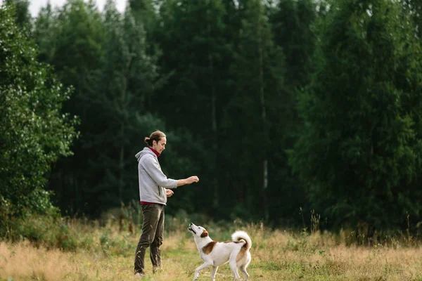 Junger Mann spielt mit seinem Hund in der Natur. — Stockfoto