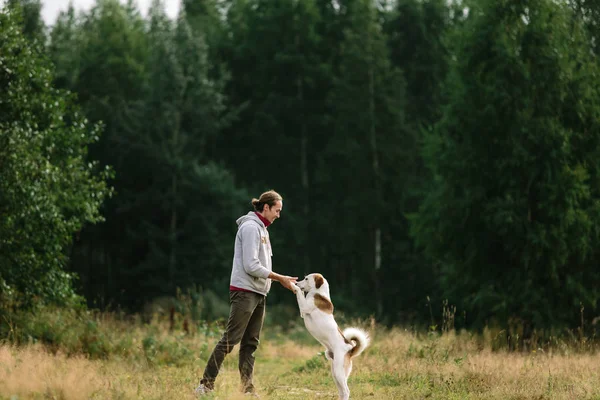 Genç adam doğa adlı köpeğiyle oynuyor. — Stok fotoğraf