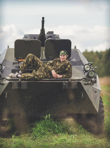 Ein Mann liegt auf einem Militärfahrzeug auf einem Feld — Stockfoto