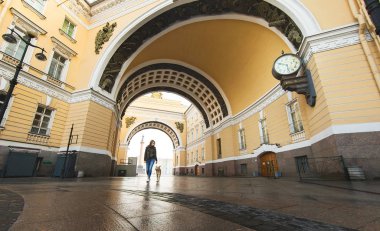 Şehir merkezindeki eski binalara karşı sokak boyunca köpeğiyle yürüyen bir kadın.