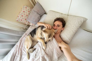 Mutlu adam, köpekle kucak kucağa uzanıyor.