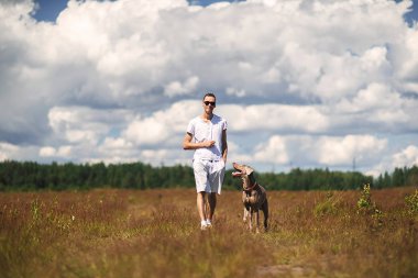 Kırsal alanda köpekle yürüyen bir adam.