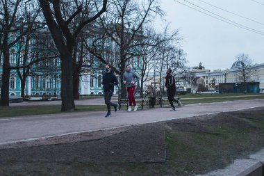 Saint-petersburg, Rusya - 31 Mart 2020: Kendini izole etmenin birinci gününde şehrin merkezinde boş sokaklar. Üç genç adam kaldırımda koşuyor.