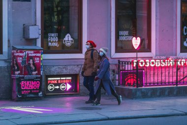 Saint-Petersburg, Rusya - 31 Mart 2020: Maskeli adam ve kadın kaldırımda yürüyor. Boş bir akşam kenti, alacakaranlıkta kendini izole etmenin ilk gününde..