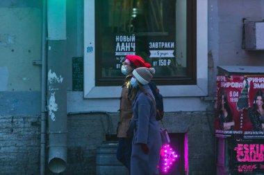 Saint-Petersburg, Rusya - 31 Mart 2020: Maskeli adam ve kadın kaldırımda yürüyor. Boş bir akşam kenti, alacakaranlıkta kendini izole etmenin ilk gününde..