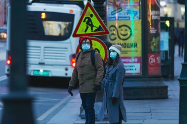 Saint-Petersburg, Rusya - 31 Mart 2020: Maskeli adam ve kadın yol kenarında duruyor ve kaldırımda el ele tutuşuyorlar. Boş bir akşam kenti, alacakaranlıkta kendini izole etmenin ilk gününde..