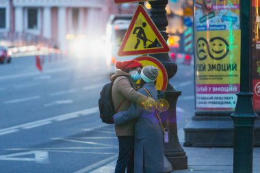 Saint-petersburg, Rusya - 31 Mart 2020: yaya geçidinde maskeli adam ve kadın kucaklaşıyor. Boş bir akşam kenti, alacakaranlıkta kendini izole etmenin ilk gününde..