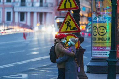 Saint-petersburg, Rusya - 31 Mart 2020: yaya geçidinde maskeli adam ve kadın kucaklaşıyor. Boş bir akşam kenti, alacakaranlıkta kendini izole etmenin ilk gününde..