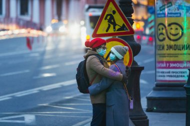 Saint-petersburg, Rusya - 31 Mart 2020: yaya geçidinde maskeli adam ve kadın kucaklaşıyor. Boş bir akşam kenti, alacakaranlıkta kendini izole etmenin ilk gününde..