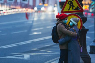 Saint-petersburg, Rusya - 31 Mart 2020: yaya geçidinde maskeli adam ve kadın kucaklaşıyor. Boş bir akşam kenti, alacakaranlıkta kendini izole etmenin ilk gününde..