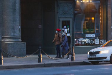 Saint-Petersburg, Rusya - 31 Mart 2020: Maskeli adam ve kadın kaldırımda yürüyor. Boş bir akşam kenti, alacakaranlıkta kendini izole etmenin ilk gününde..