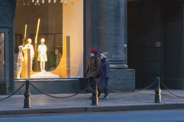 Saint-Petersburg, Rusya - 31 Mart 2020: Maskeli adam ve kadın kaldırımda yürüyor. Boş bir akşam kenti, alacakaranlıkta kendini izole etmenin ilk gününde..