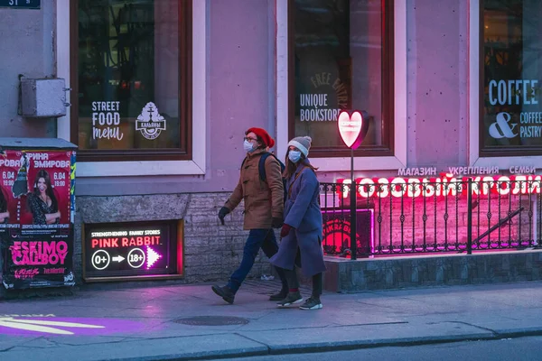 Saint-Petersburg, Rusya - 31 Mart 2020: Maskeli adam ve kadın kaldırımda yürüyor. Boş bir akşam kenti, alacakaranlıkta kendini izole etmenin ilk gününde..