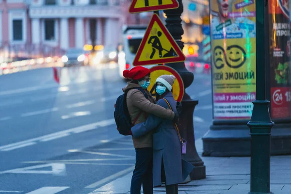 Saint-petersburg, Rusya - 31 Mart 2020: yaya geçidinde maskeli adam ve kadın kucaklaşıyor. Boş bir akşam kenti, alacakaranlıkta kendini izole etmenin ilk gününde..