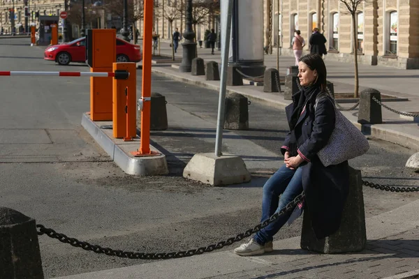 ロシア サンクトペテルブルク 2020年4月7日 ネフスキー プロスペクト ヴォスタニヤ広場 モスクワ駅の近くの歩道に座っている黒いコートの疲れている女性 — ストック写真