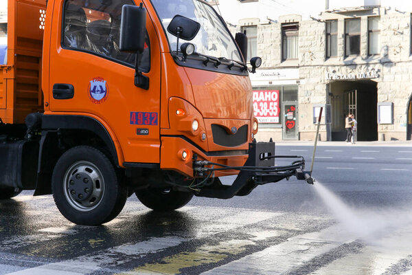 Saint-petersburg, Russia - 7 April 2020: Orange sweeper for cleaning of streets, watering the sidewalk on the Nevsky Prospekt