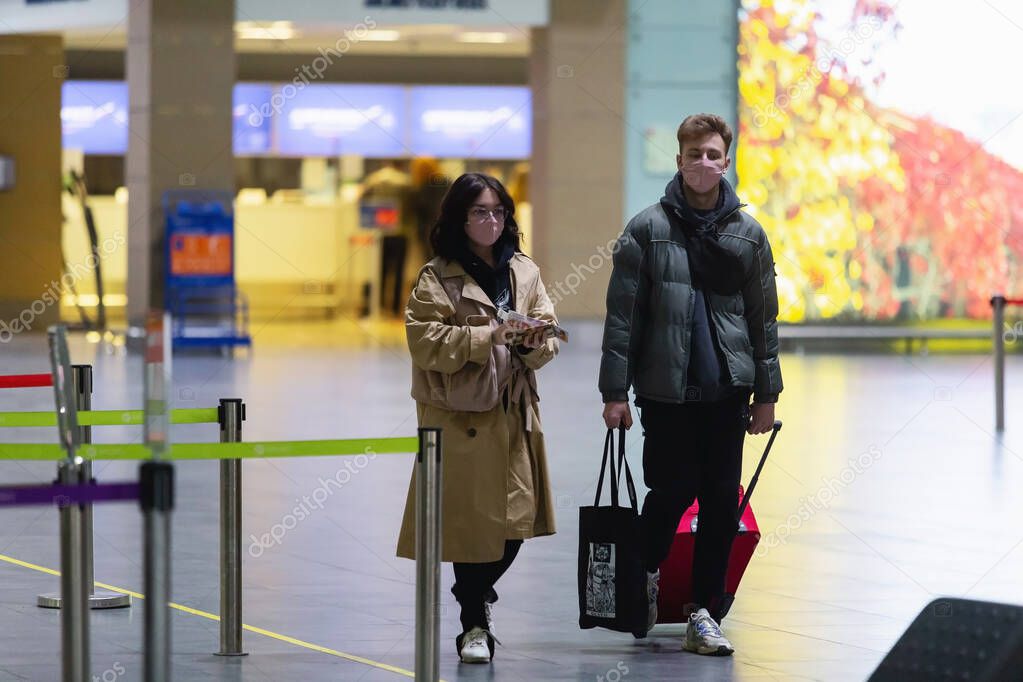 Saint-Petersburg, Russia, 30 April 2020: Man and woman in masks with baggage walking inside Pulkovo International Airport. Due to coronavirus pandemic international flights canceled