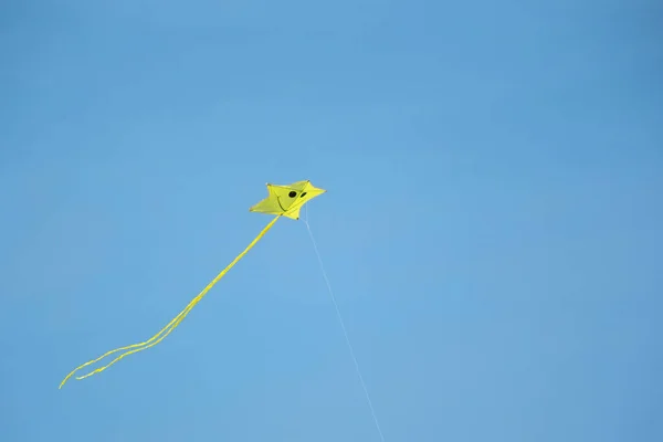 蓝色天空中飘扬的黄色小风筝 — 图库照片