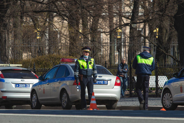 Saint-Petersburg, Russia - May 1 2020: Traffic policeman controls the traffic in the city center. Several police cars are parked along the road. Strengthening before the victory day holiday