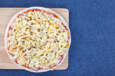 Üstten Görünüm ile mavi masa örtüsü üzerinde ahşap tahta üzerinde ham pizza