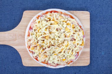 Üstten Görünüm ile mavi masa örtüsü üzerinde ahşap tahta üzerinde ham pizza