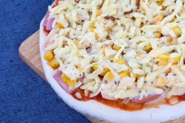 Üstten Görünüm ile mavi masa örtüsü üzerinde ahşap tahta üzerinde ham pizza