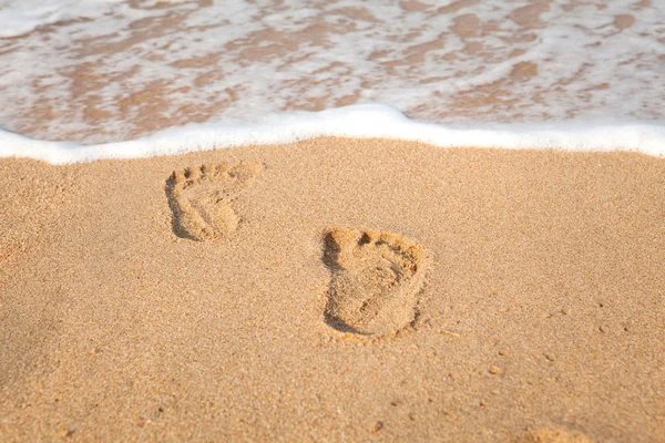 Pieczęć stóp na piasku na plaży w promieniach słońca na rano — Zdjęcie stockowe