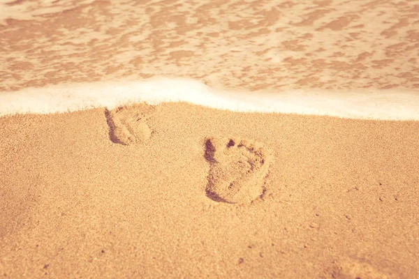 Pieczęć stóp na piasku na plaży w promieniach słońca na rano, — Zdjęcie stockowe