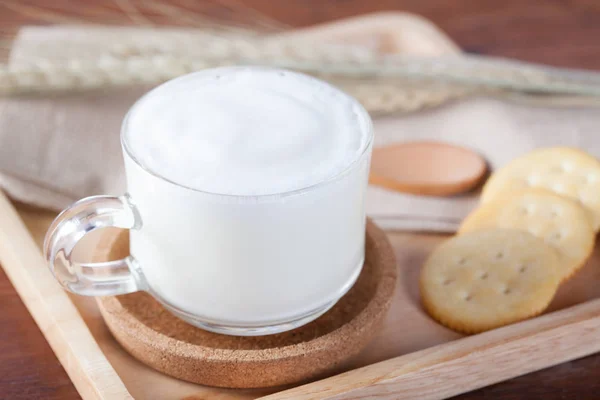 Hot milk with biscuits on wooden plate on wooden table for break