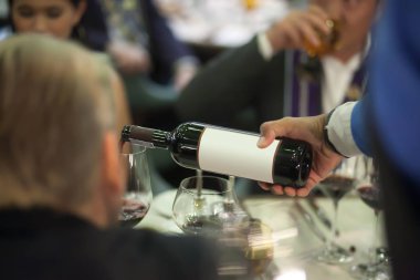 Garsona kırmızı şarap şarap cam lüks akşam yemeği partisi, bulanık arka plan hizmet için masaya dökülen.