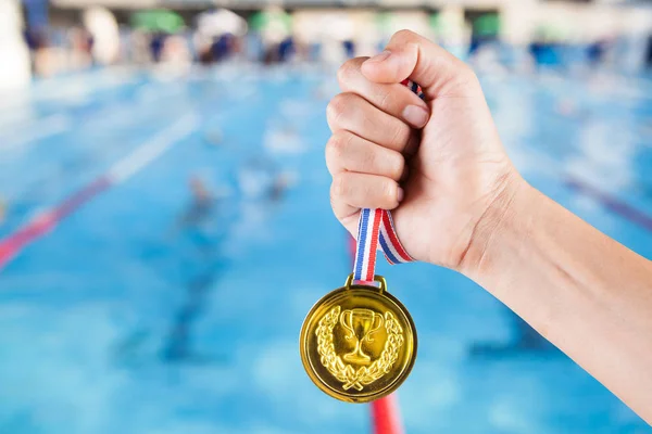 Maroknyi ázsiai ember tartja elmosódott háttér, a medence és a úszás verseny aranyérmes. — Stock Fotó