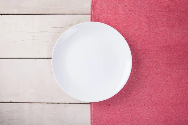 Kırmızı masa örtüsü ve kopyalama yeri olan beyaz ahşap masa boş beyaz plaka üstten görünüm koymak.
