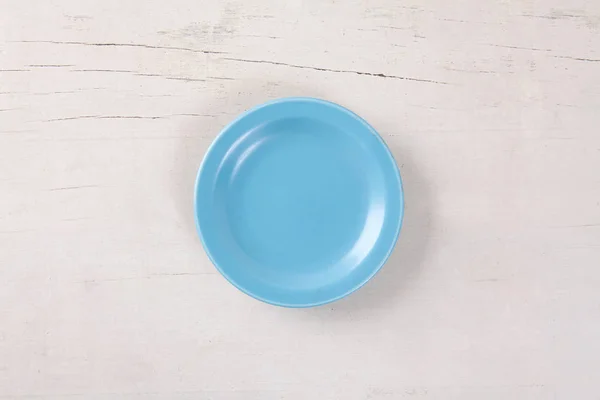 Vista dall'alto del piatto blu vuoto messo sul tavolo di legno bianco con spazio per la copia . — Foto Stock
