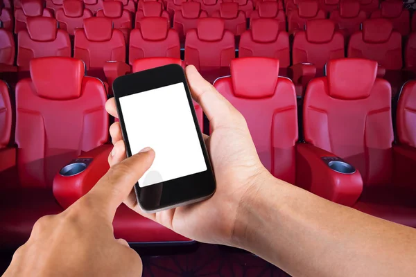 Smartphone på hand och vit skärm med suddig bakgrund av sätet i biograf. — Stockfoto