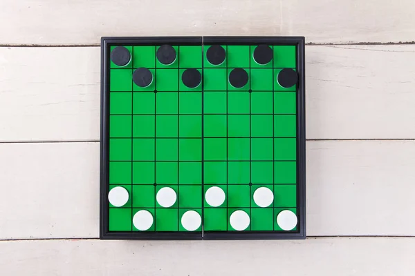 Start checker game on green board view from above on wood table.