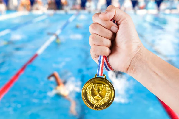 Puñado de asiático hombre celebración de la medalla de oro con fondo borroso de la piscina . — Foto de Stock