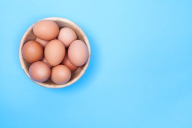 Tavuk yumurta alan kopya mavi zemin üzerine ahşap kase 